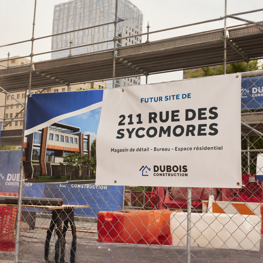  Une banderole en vinyle avec œillets, accrochée à une clôture, faisant la promotion d’un nouveau bâtiment commercial à usage mixte.
