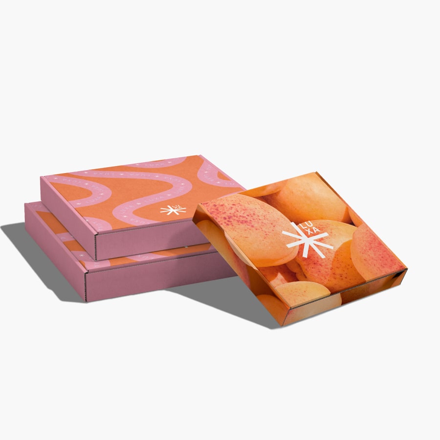 Trois boîtes carrées pour envoi postal posées à plat, affichant le nom de la marque sur le couvercle supérieur.