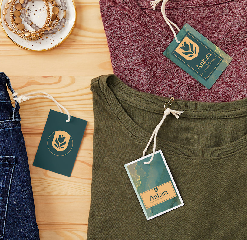 Étiquettes volantes en plastique, accrochées par un fil à des chemises et des jeans exposés sur un comptoir de bois.