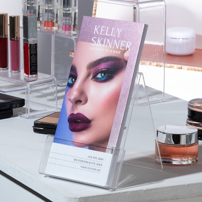 Cartons d’information avec accents métallisés violet scintillant, créés par une maquilleuse et présentés sur le comptoir d’un salon de beauté.