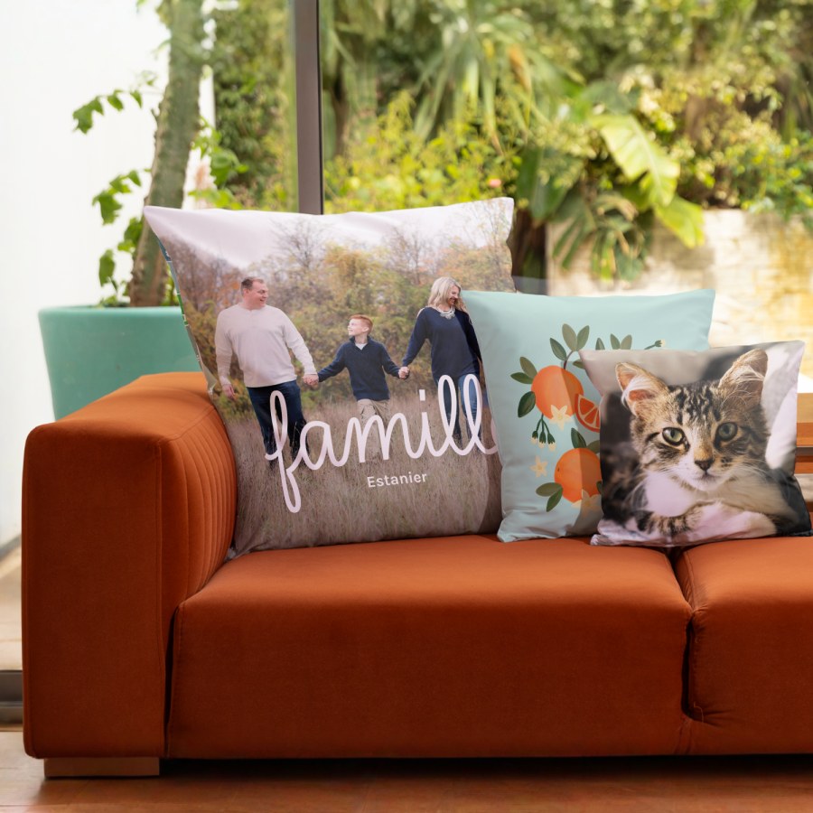 Trois coussins personnalisés avec la photo d’une famille, un graphisme avec des oranges et la photo d’un chat. 