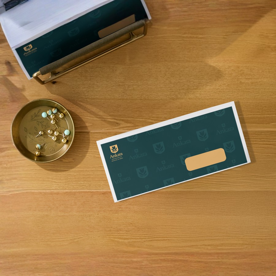 Enveloppe commerciale sur un bureau, ornée d’un logo dans le coin supérieur gauche avec un champ d’adresse visible sur le devant.