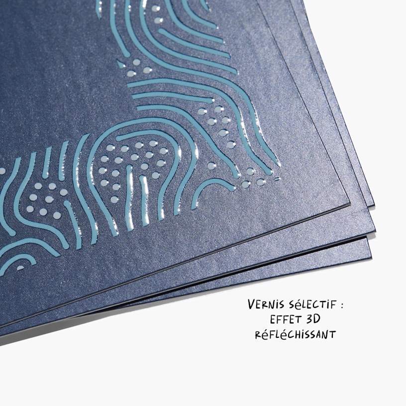 Gros plan sur des cartes de visite vernis sélectif avec inscription embossée glacée créant un aspect réfléchissant en 3D.