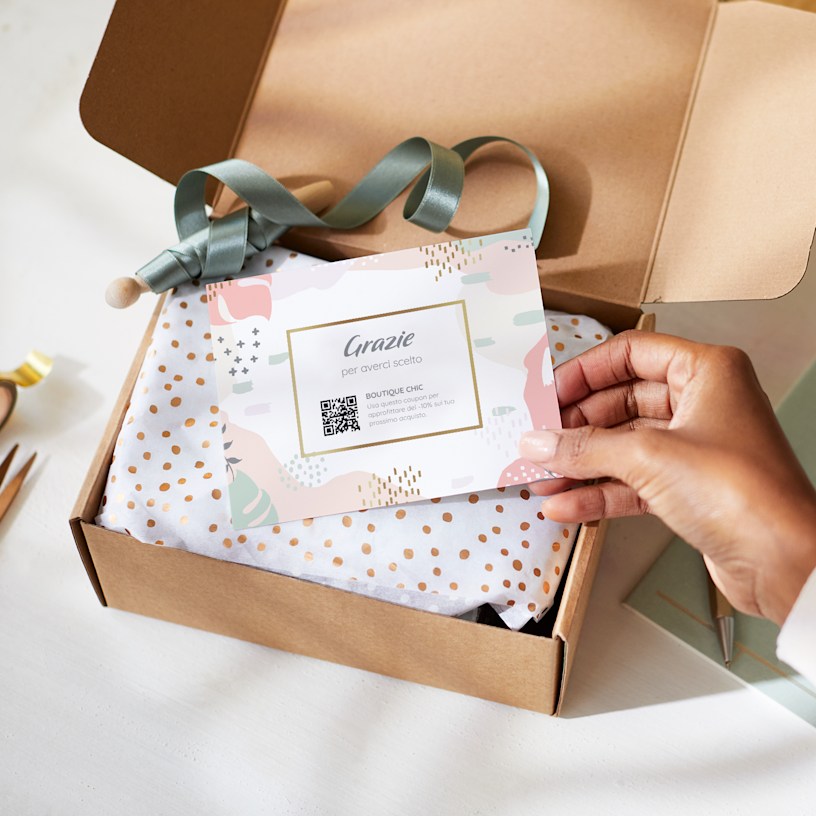 Una persona tiene in mano un biglietto di ringraziamento incluso insieme a una confezione regalo.