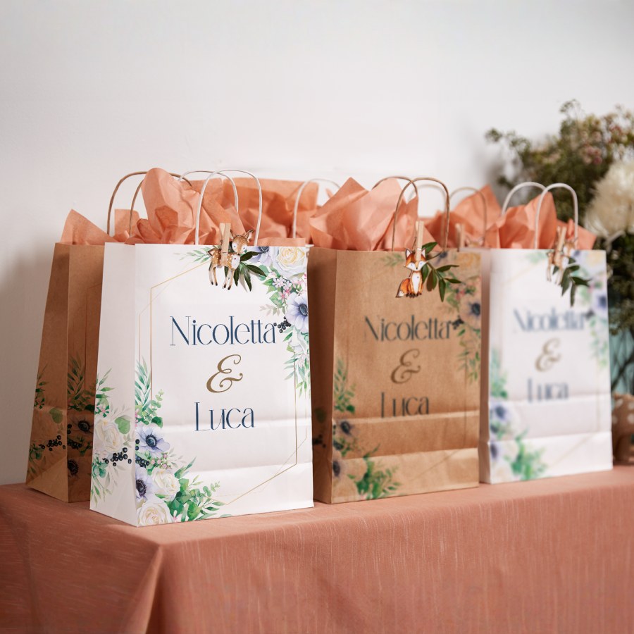 Tre sacchetti per regali personalizzati con motivi a fiori per un matrimonio e riempiti con carta velina rosa salmone.