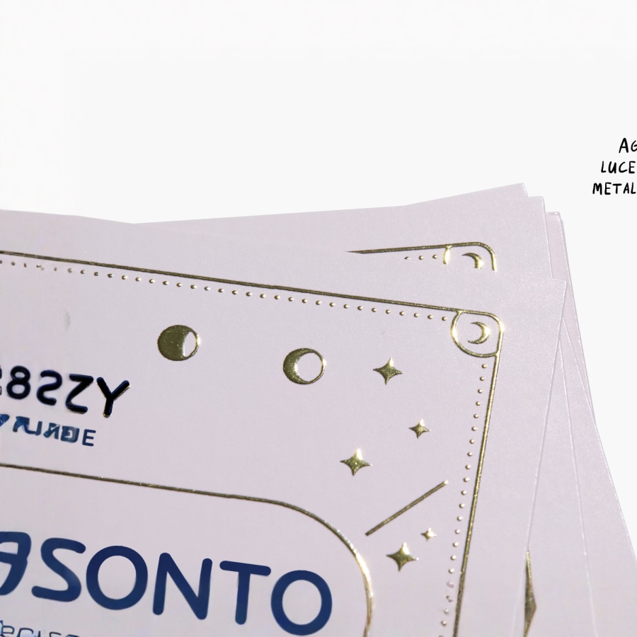 Primo piano di un biglietto da visita raffigurante un logo e una scritta metallizzati color oro in rilievo.