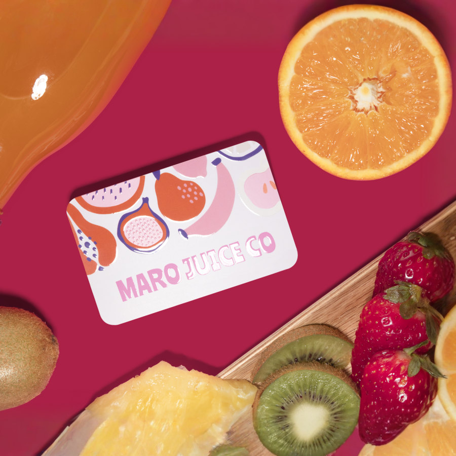 Un biglietto da visita con vernice UV per un negozio di succhi, posizionato su un tavolo con della frutta fresca appena tagliata.