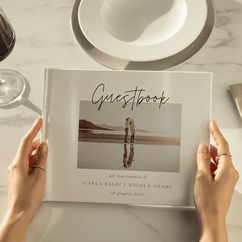 Un guestbook di nozze tra le mani di una persona, con la stampa della foto di una coppia sulla copertina. 