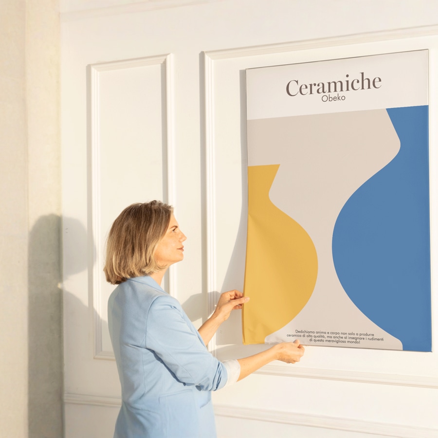 Donna che monta una nuova stampa su tessuto per un’azienda di ceramiche sulla relativa struttura senza soluzione di continuità.