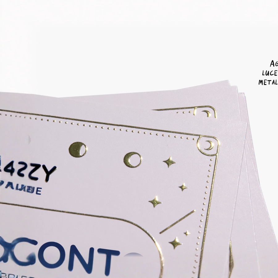 Primo piano di un biglietto da visita raffigurante un logo e una scritta metallizzati color oro in rilievo.