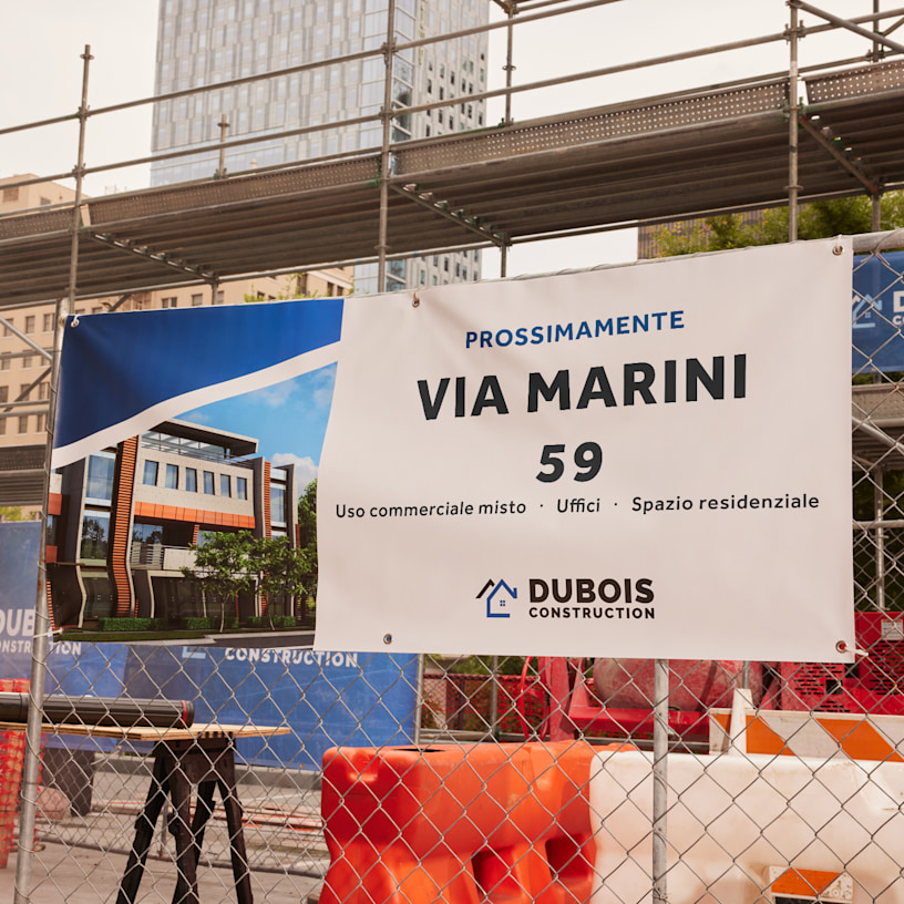 Lo striscione di un’impresa edilizia fissato al cancello di un cantiere, con dettagli sulla nuova costruzione in corso.