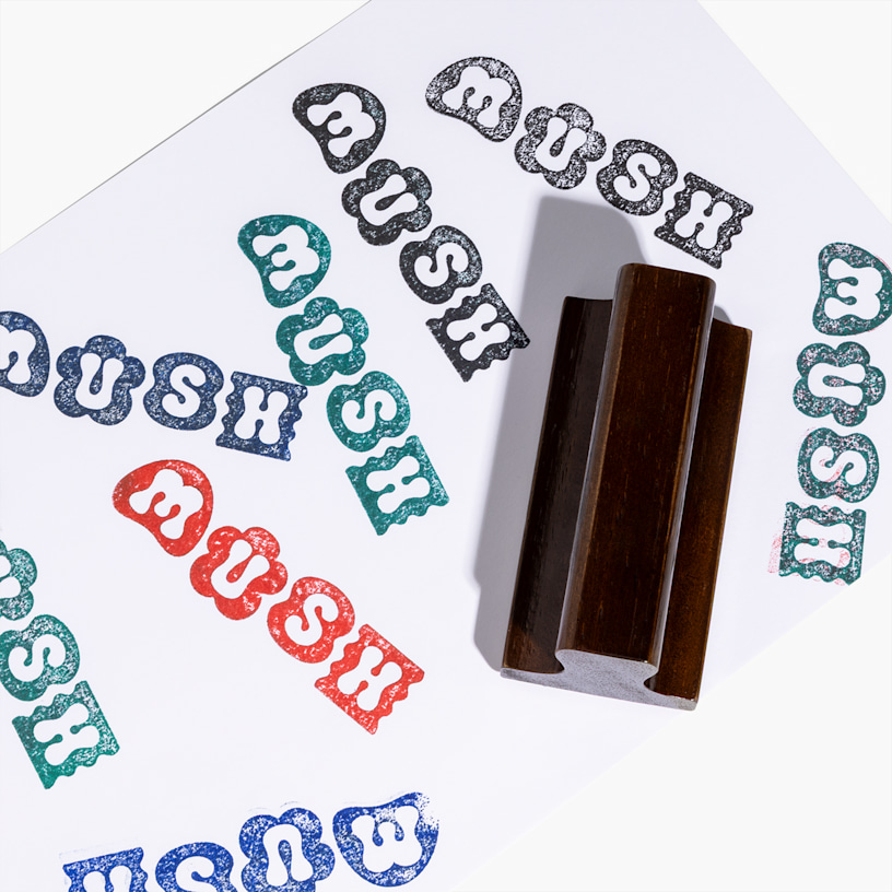 Un timbro in gomma personalizzato che riproduce impronte ripetute di un logo in inchiostro nero, blu petrolio, blu e rosso su carta bianca.