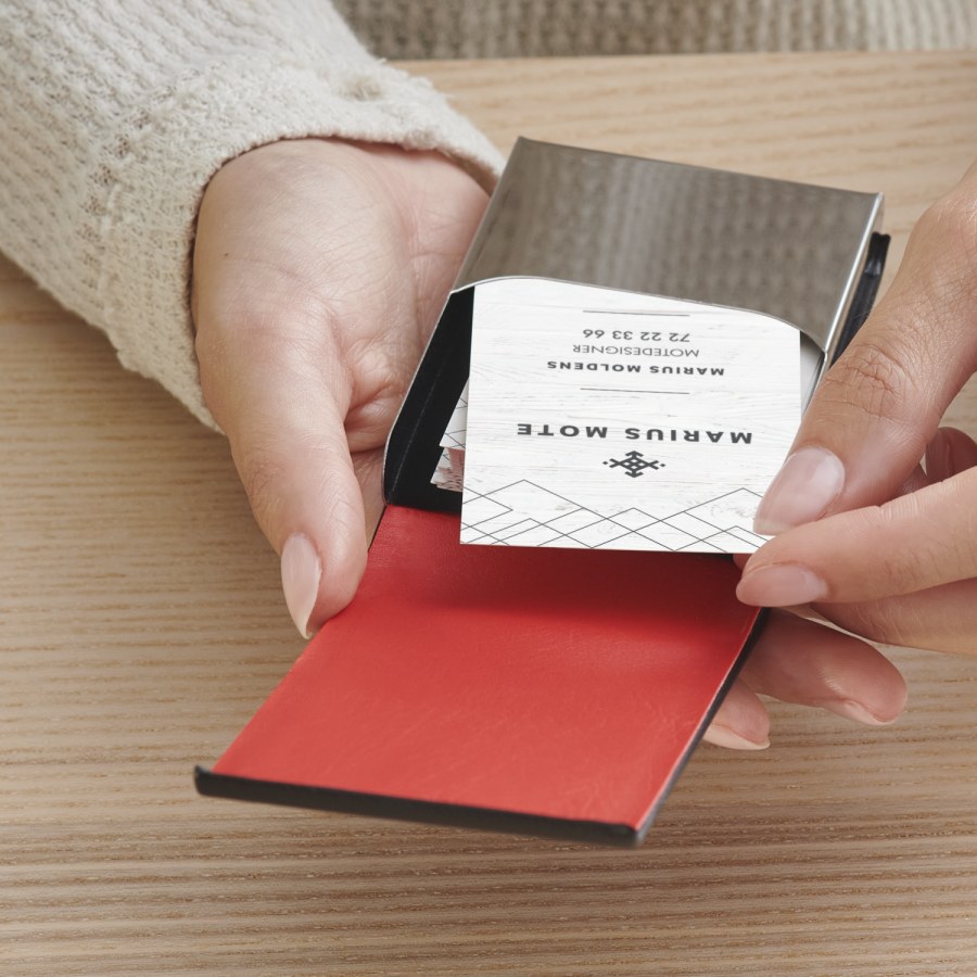 En kvinne tar et kort fra en vertikal visittkortholder i sort lær.