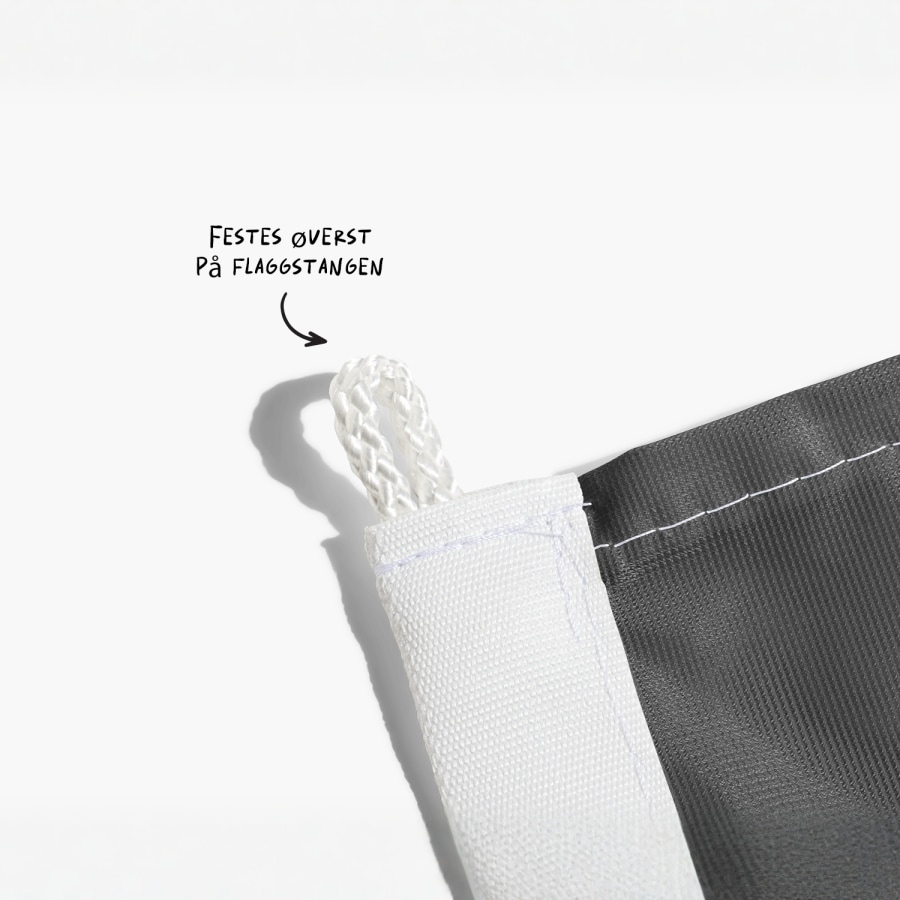Et nærbilde av festet øverst på flagget med en merknad om å feste denne delen til flaggstangen.