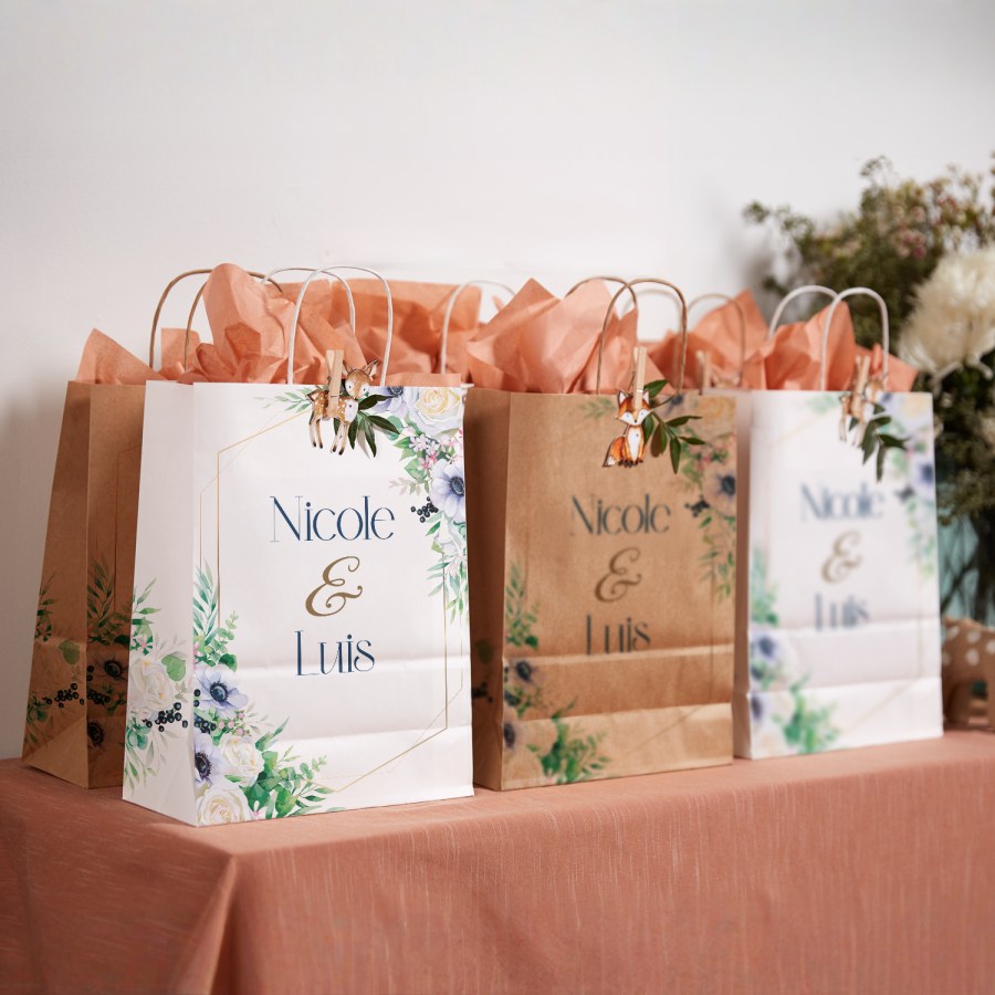 Tre gaveposer fra en bryllupsfest med blomstermønster fylt med lakserosa pakkepapir med trykk.