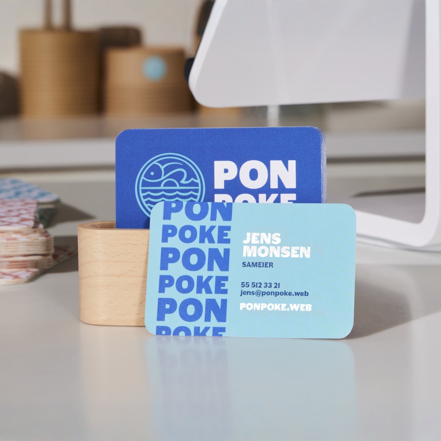 Et sett med blå og hvite visittkort med avrundede hjørner for en pokérestaurant plassert på disken.