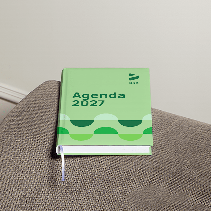 Een hardcover agenda met reclame voor een ontwerpbedrijf op de armleuning van een bank.