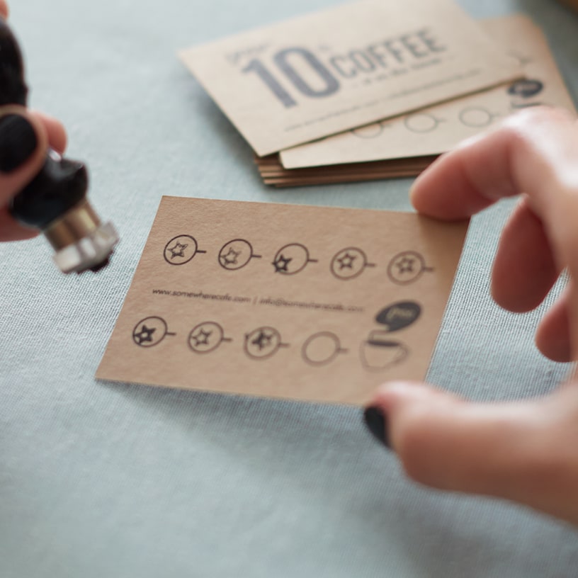 Weergave van dichtbij van iemands hand die een inktstempel vasthoudt en op het punt staat om een klantkaartje te stempelen.