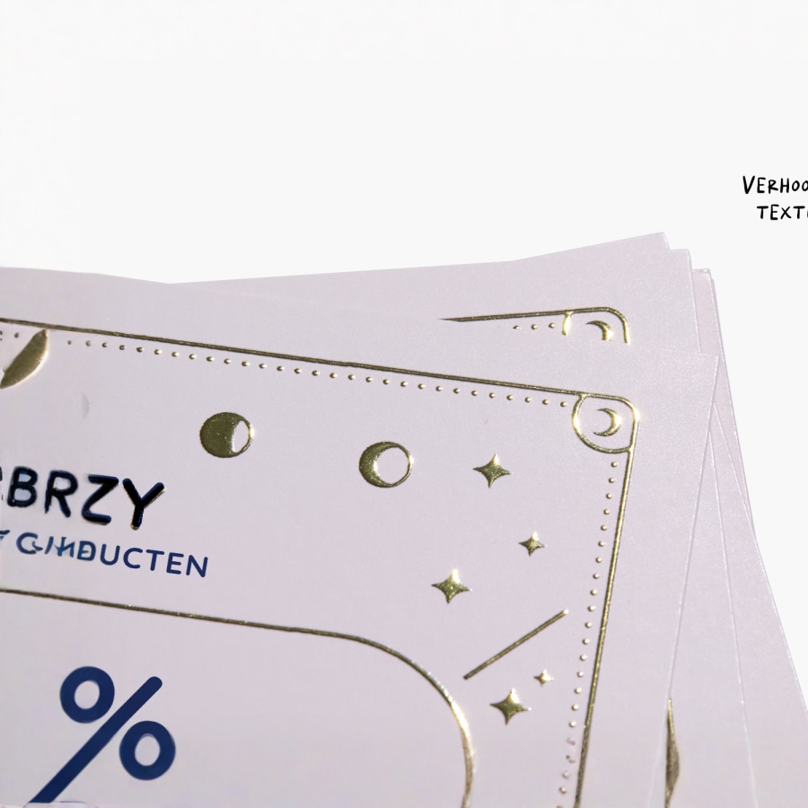 Een close-up van een visitekaartje met logo en tekst in gouden foliedruk.