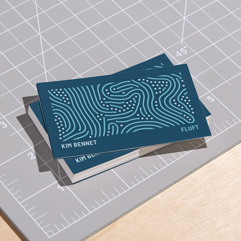 Een stapel persoonlijke, matte visitekaartjes op een snijmat.