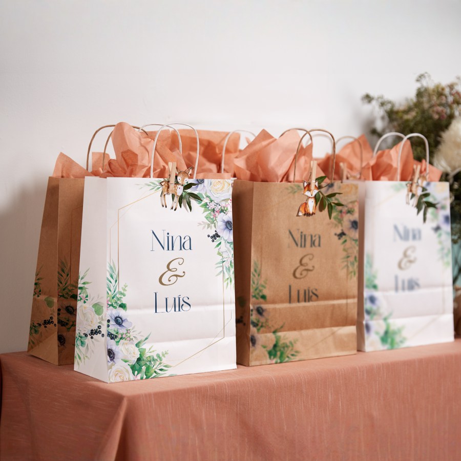 3 sacos para presentes, distribuídos no contexto da celebração de um casamento, com padrão floral e papel de seda cor de salmão no interior.