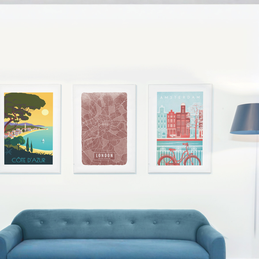 Três molduras em tecido com diferentes cidades europeias, em exposição numa sala de estar.
