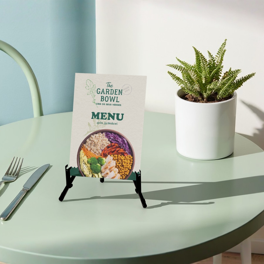 Menu em PVC expandido Forex exposto num suporte de madeira sobre uma mesa de restaurante.