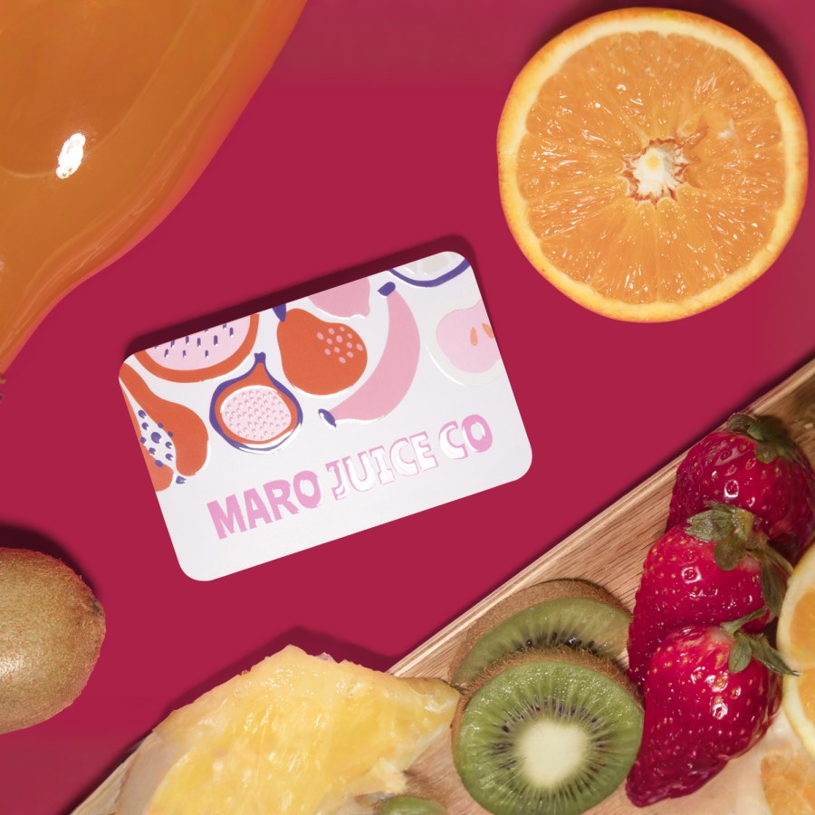 Um cartão de visita com verniz UV, para um espaço de restauração especializado em sumos, em cima de uma mesa com fruta acabada de cortar.