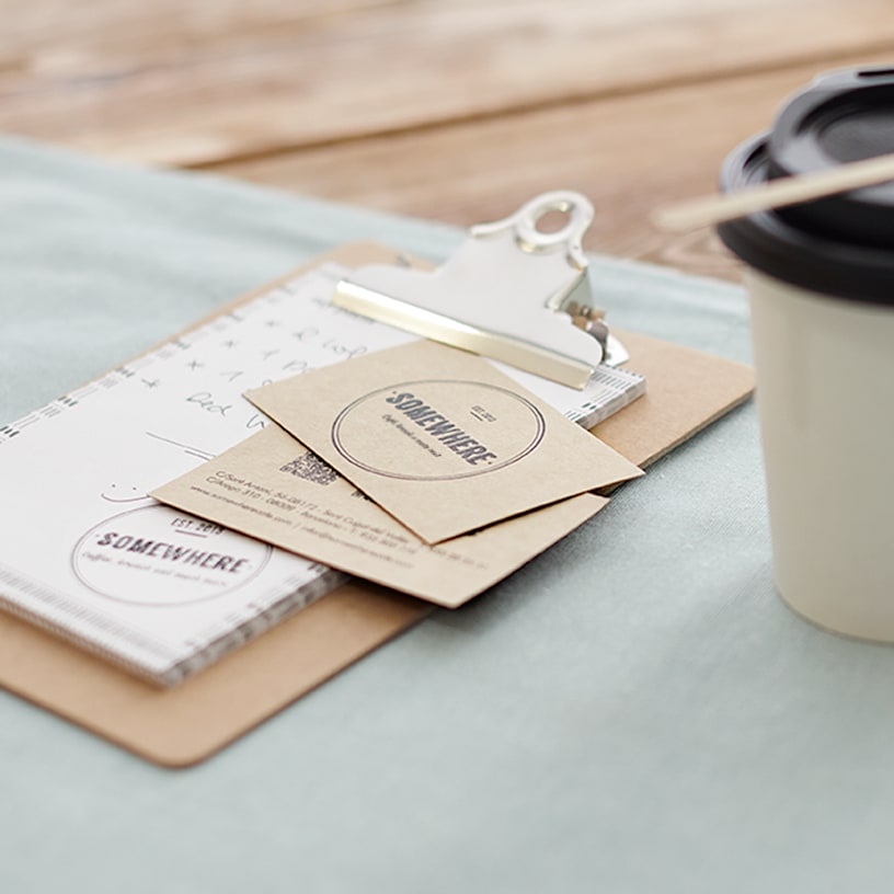 Dois sacos de tamanho padrão em papel robusto ao lado de um copo de café para levar.