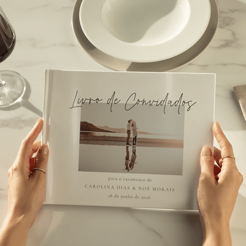 Mãos a segurar um livro de convidados de casamento personalizado com uma foto dos noivos na capa. 