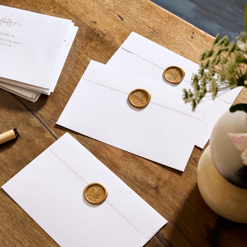 Envelopes brancos com selos de cera florais dourados. 