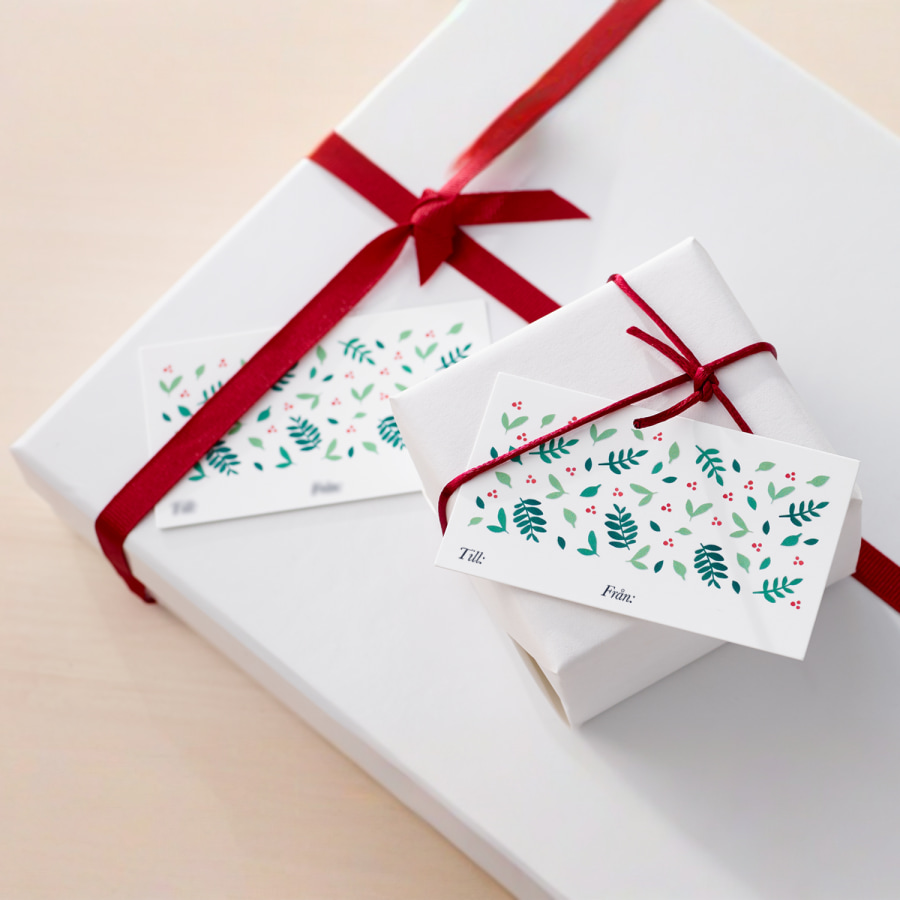 En specialdesignad presentetikett med juldesign instoppad bakom snöret till ett inslaget paket. 