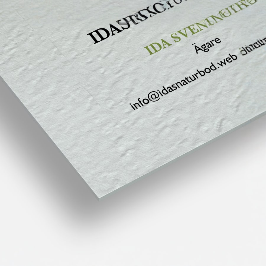 En närbild av visitkort av obestruket strukturerat papper med fyrkantiga hörn och kanvasliknande struktur på pappret.