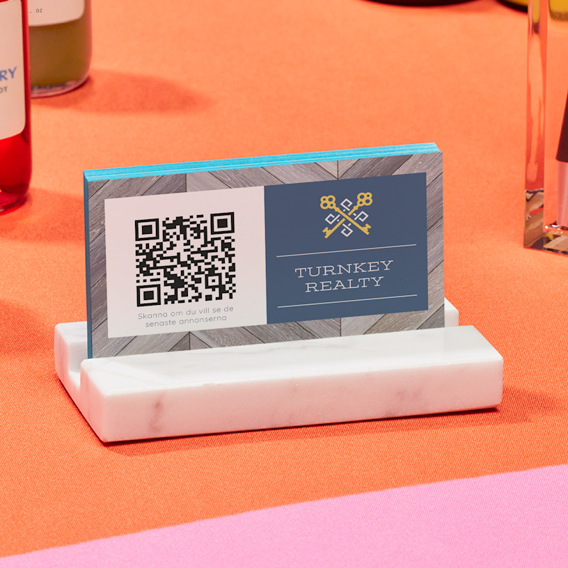 En visitkortshållare i marmor med visitkort med QR-kod för en person som heter Raúl Benítez.