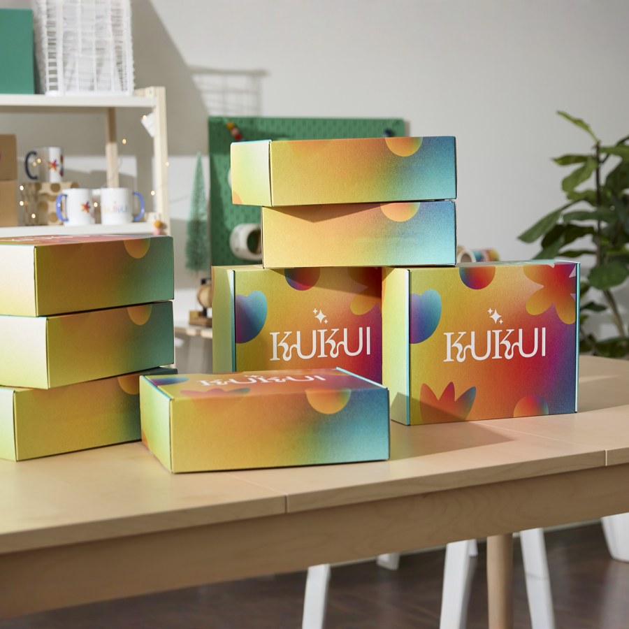 A stack of mailing boxes promoting a scented candle business, displayed on a table.