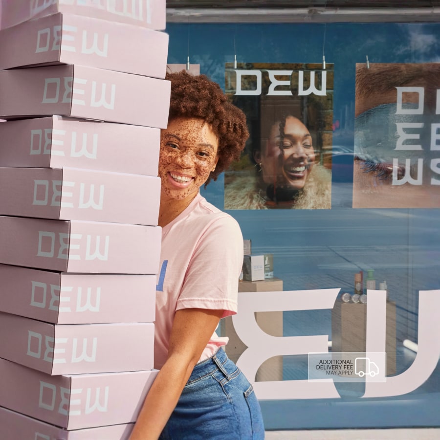 A person carrying a big stack of mailing boxes promoting a beauty & apparel brand.