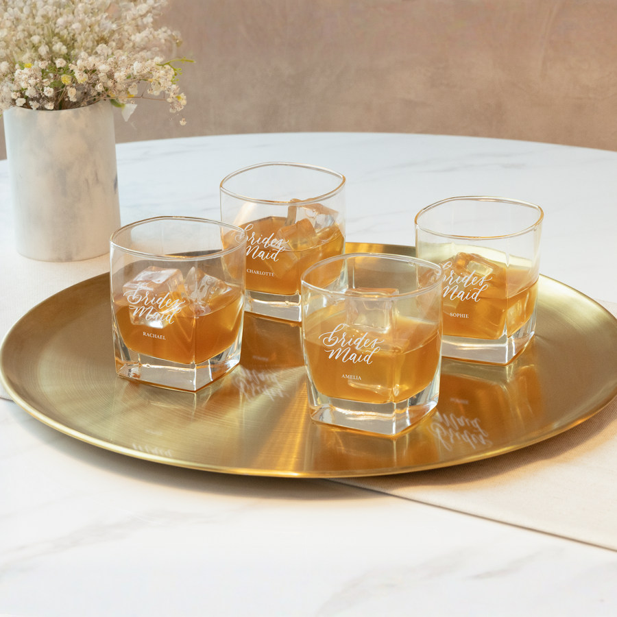 Four tumbler glasses personalised and engraved for groomsmen at a wedding.