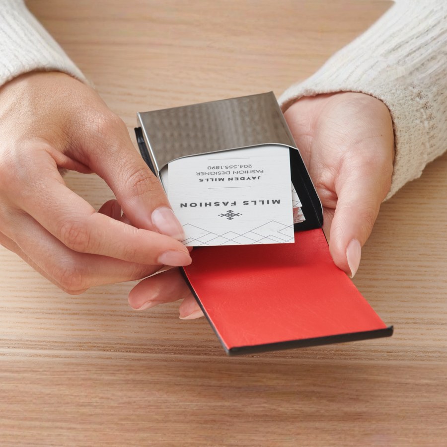 A woman is removing a card from a black leather vertical business card holder.