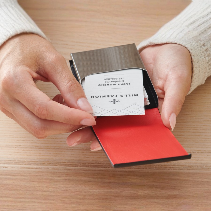 Una señora que retira una tarjeta de un tarjetero vertical de piel color negro.