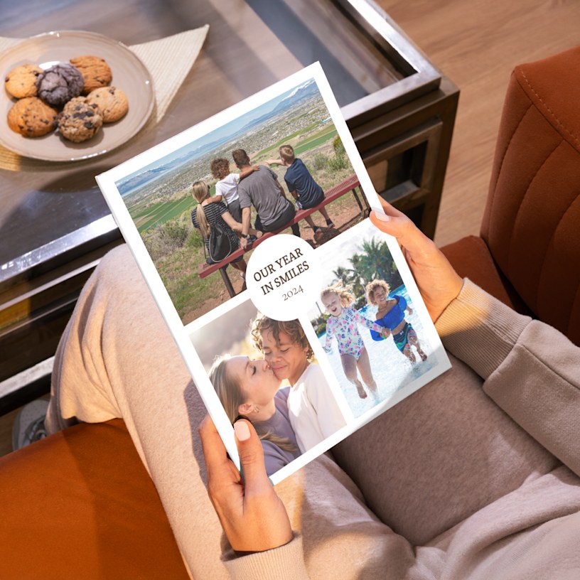 A pair of hands holding a family photo book ent itled, “Our Year in Smiles.” 