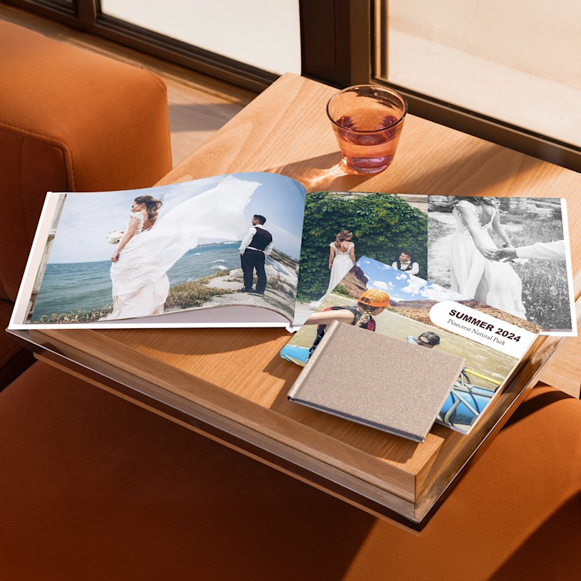 Photo books in a variety of sizes displayed on a living room table. One book is open to a spread of wedding photos. 