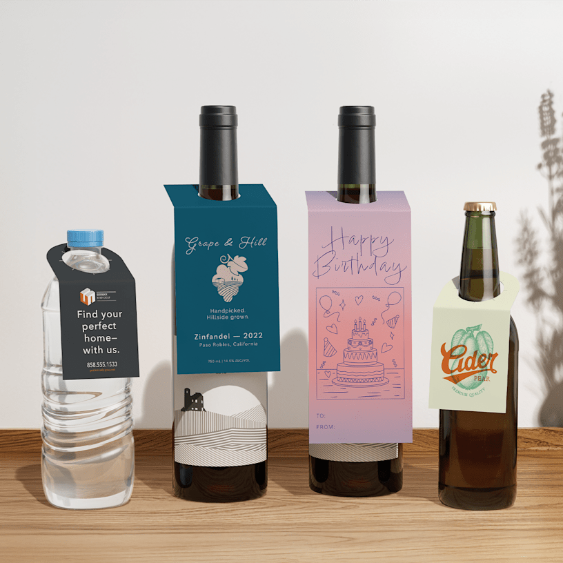 A water bottle, two wine bottles and a cider bottle displaying bottle neck tags.
