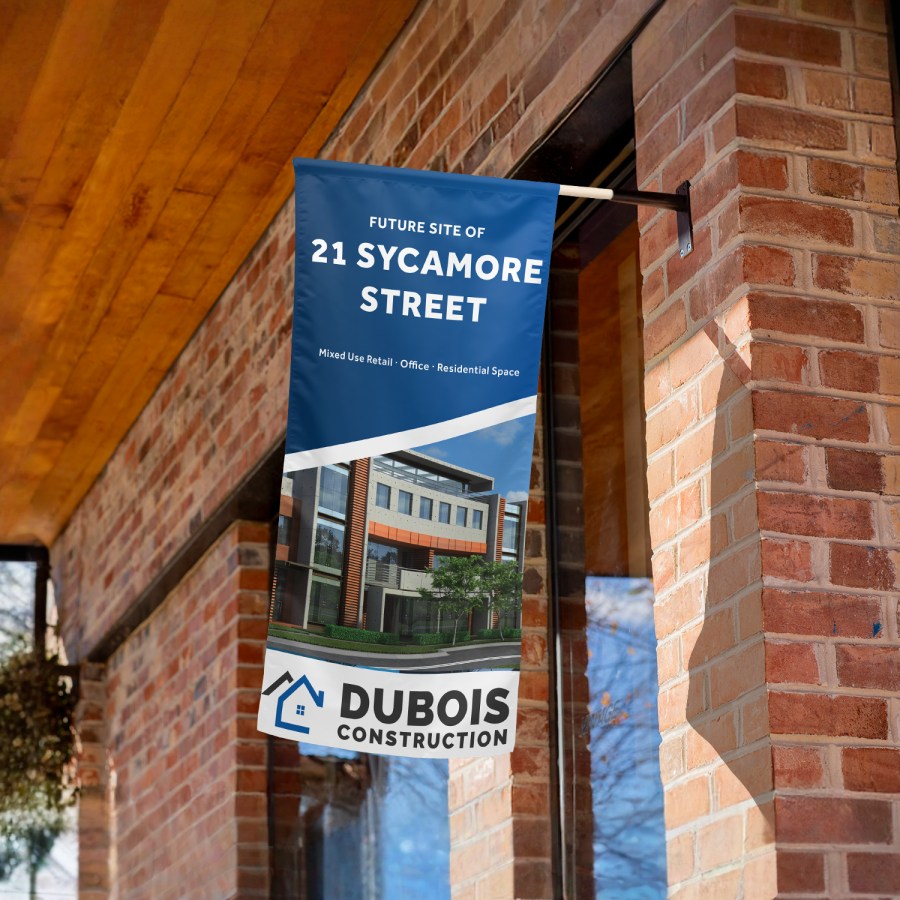 A wall flag promoting a construction business, displayed at the corner of a building.
