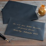 A black custom envelope addressed in gold-colored ink.