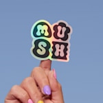 A holographic sticker cut to the shape of a handmade jewelry company’s logo.