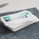 A stack of rounded rectangle business cards from a home contracting company, with the name Richard Suarez in large, embossed gloss letters.