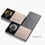 A stack of gold raised foil appointment cards and a stack of silver raised foil appointment cards, both for the same spa and using the same design.