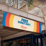 A colorful hanging vinyl banner promoting free donuts.