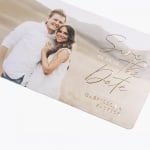A custom save the date card featuring a photo of a couple and embossed foil detailing. 
