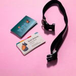 Two stacks of embossed gloss business cards, showing the front and back of a design for a dogwalking business. A dog collar is sitting next to them.